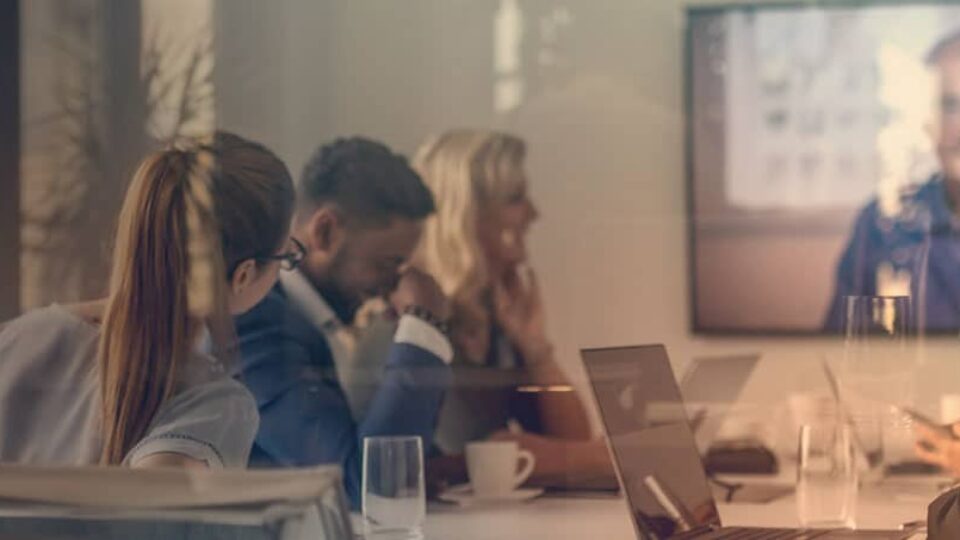 Vier Menschen und ein Monitor mit einer Video-Konferenz