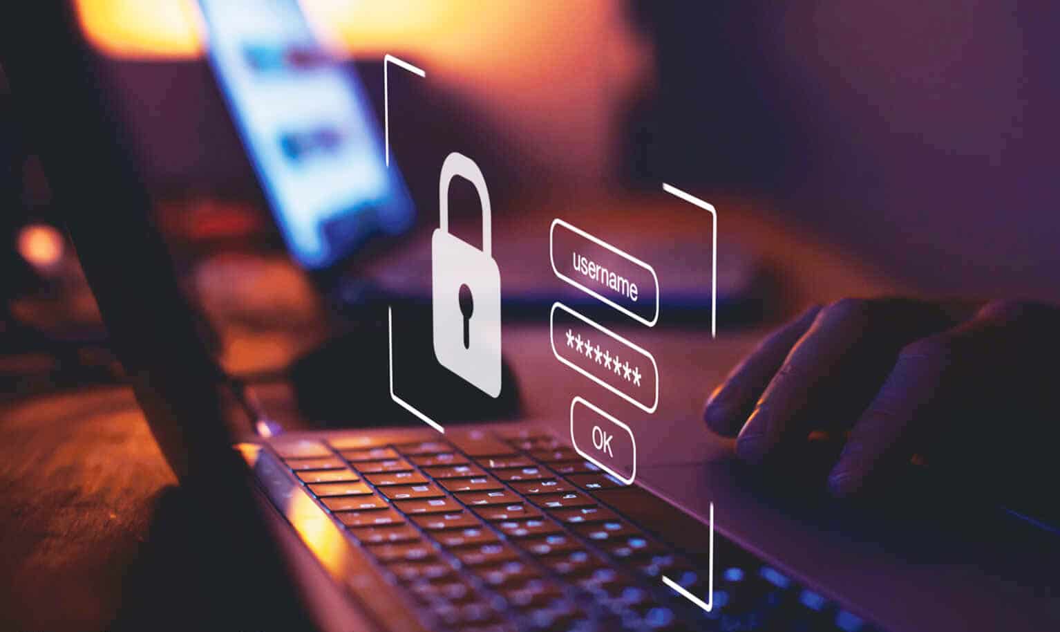 Nahaufnahme eines Laptops mit digitalem Sicherheitsschloss und Login-Eingabefeldern im Dunkeln.